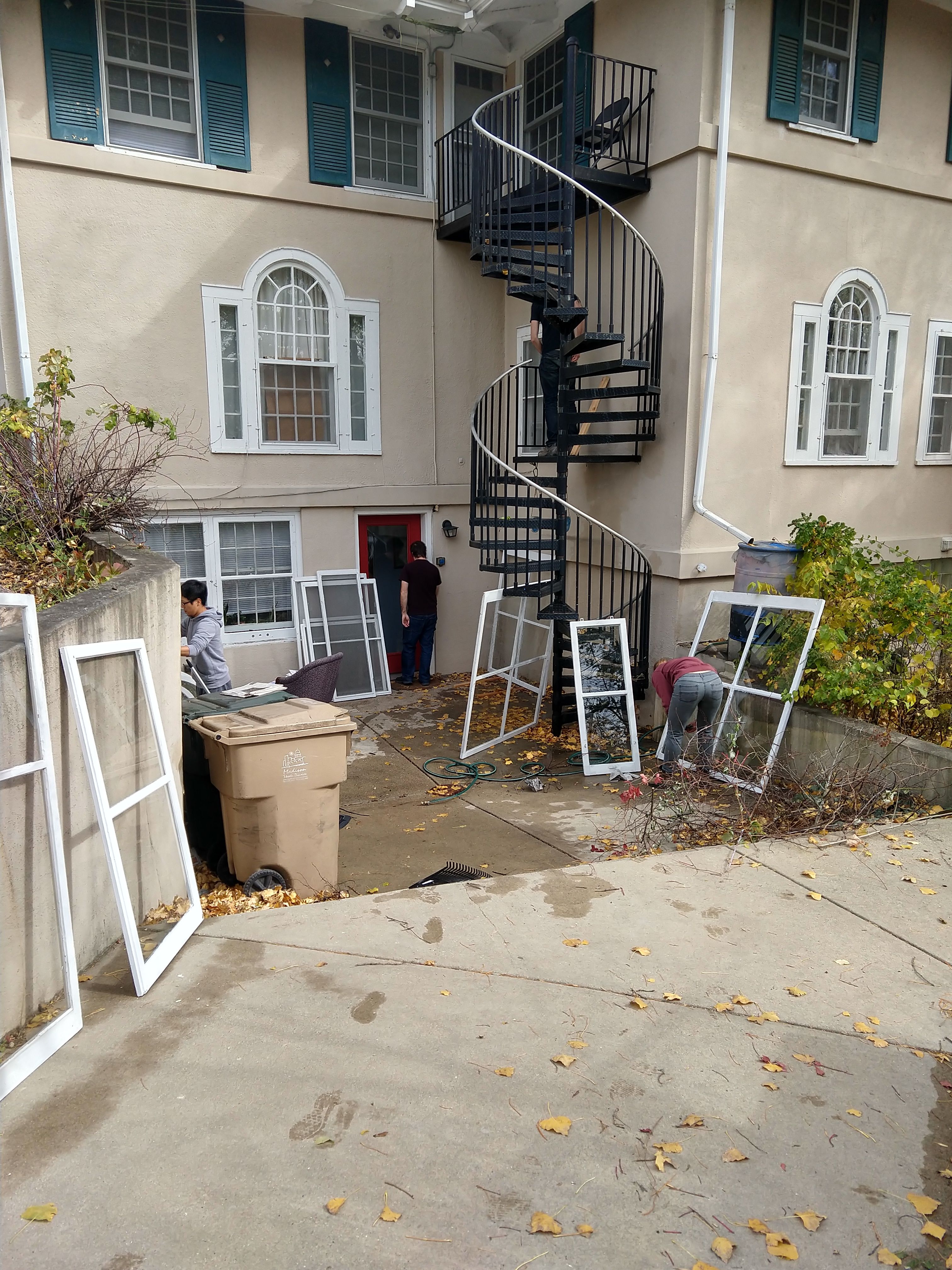 House storm windows being prepared for installation on Work Weekend. The windows have been cleaned and are leaning against the house. (Circa fall 2020)