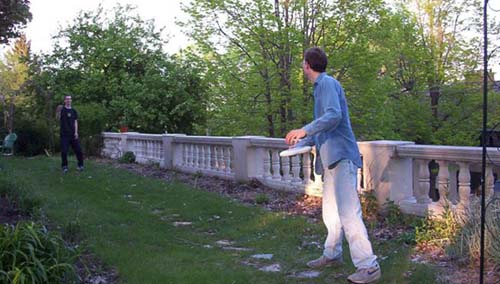 Two Summiteers toss a frisbee next to the house