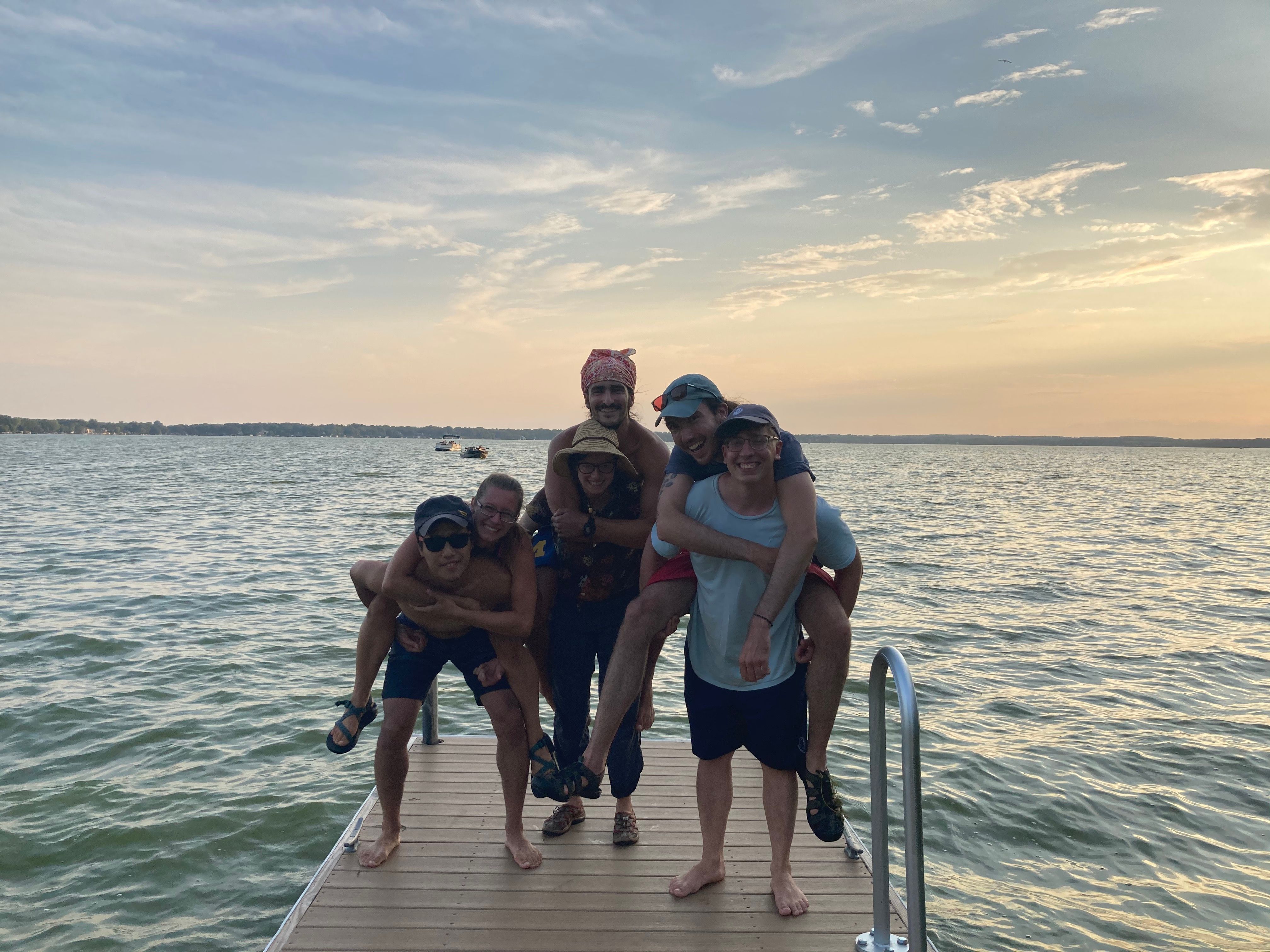 Six Summiteers pose victoriously after canoeing five lakes. Three people each posing with one person on their back. (Circa summer 2020)