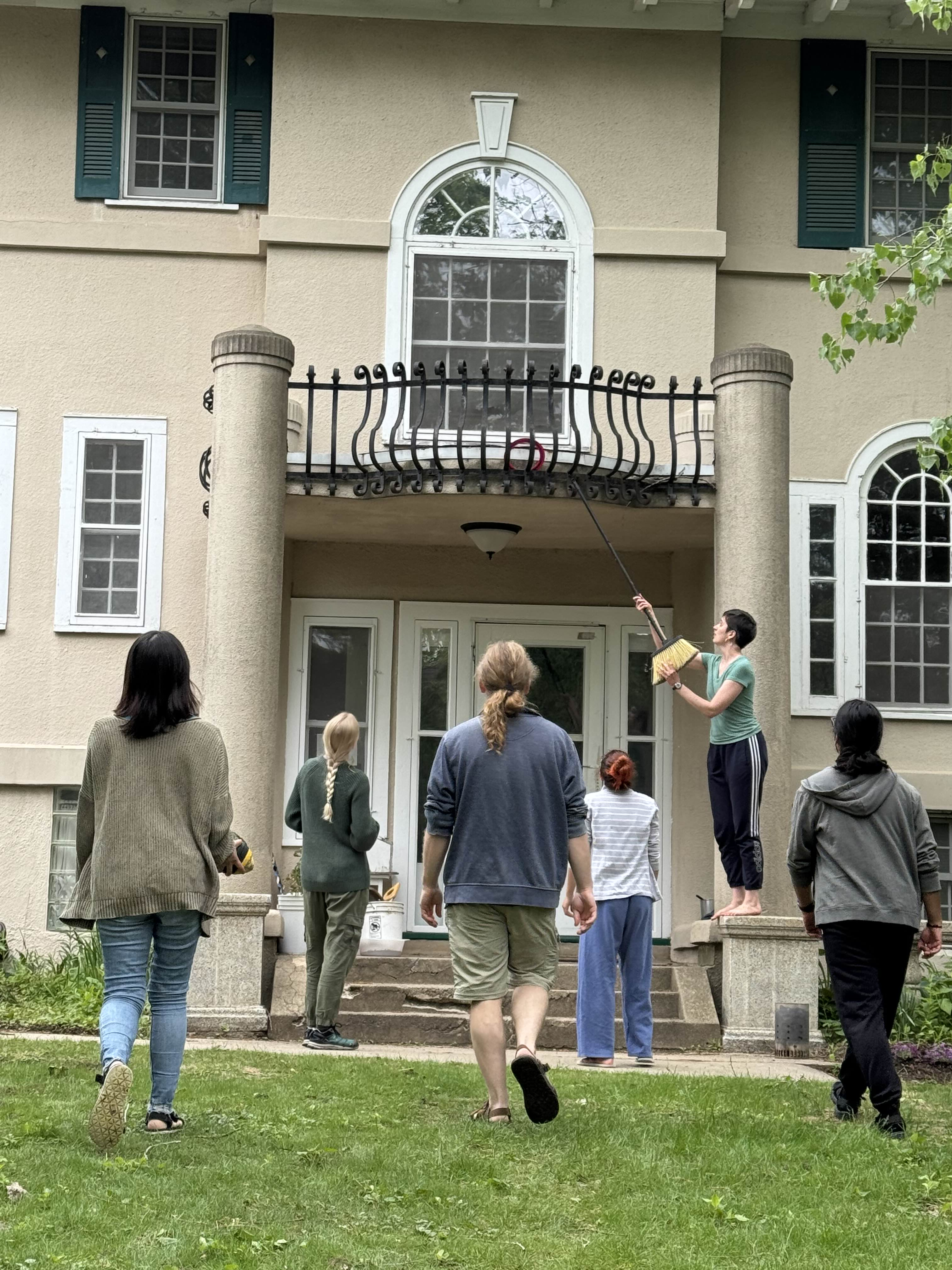 Six Summiteers in front of the house trying to recover a frisbee stuck in the balcony