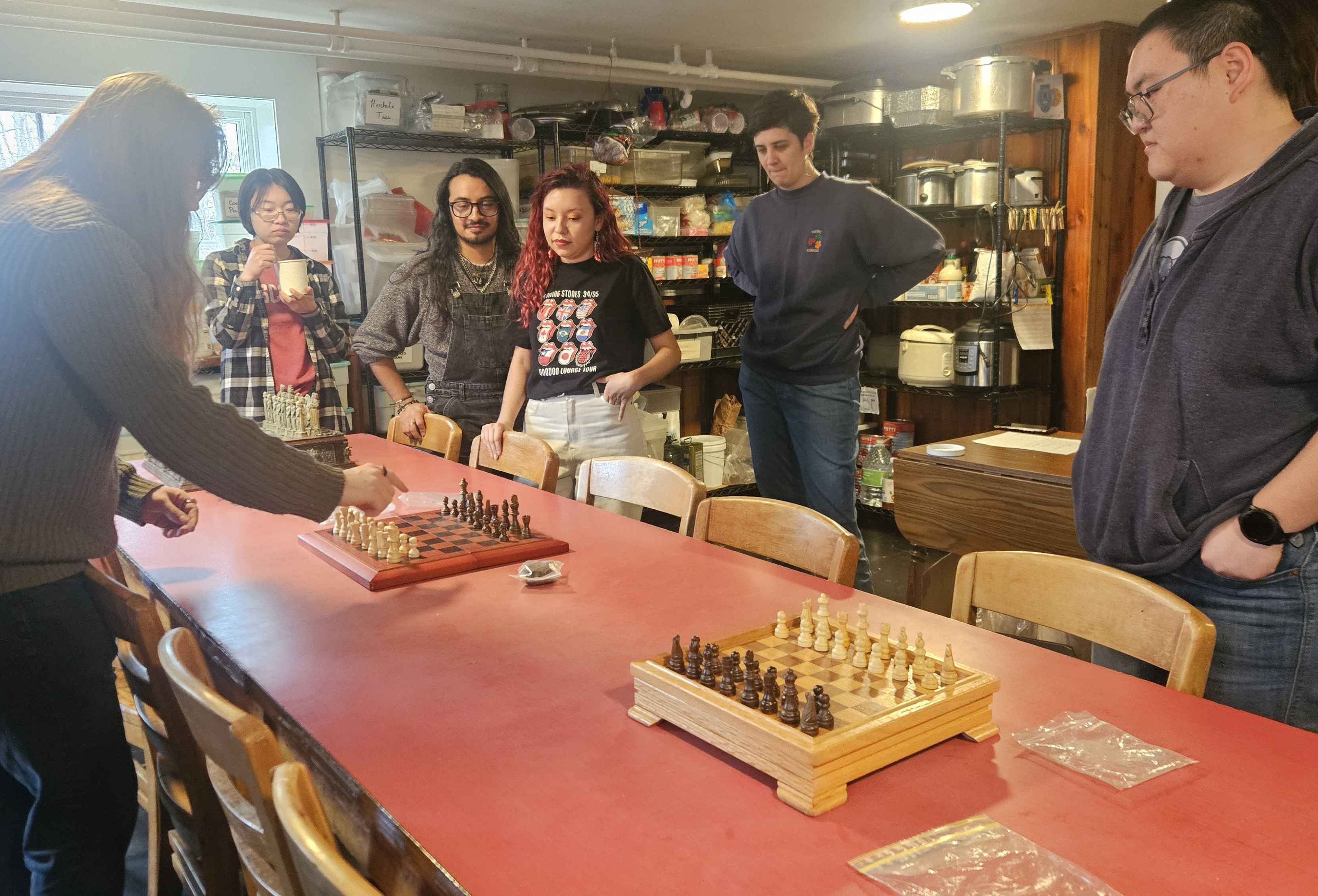 Six Summiteers stand around three chess boards