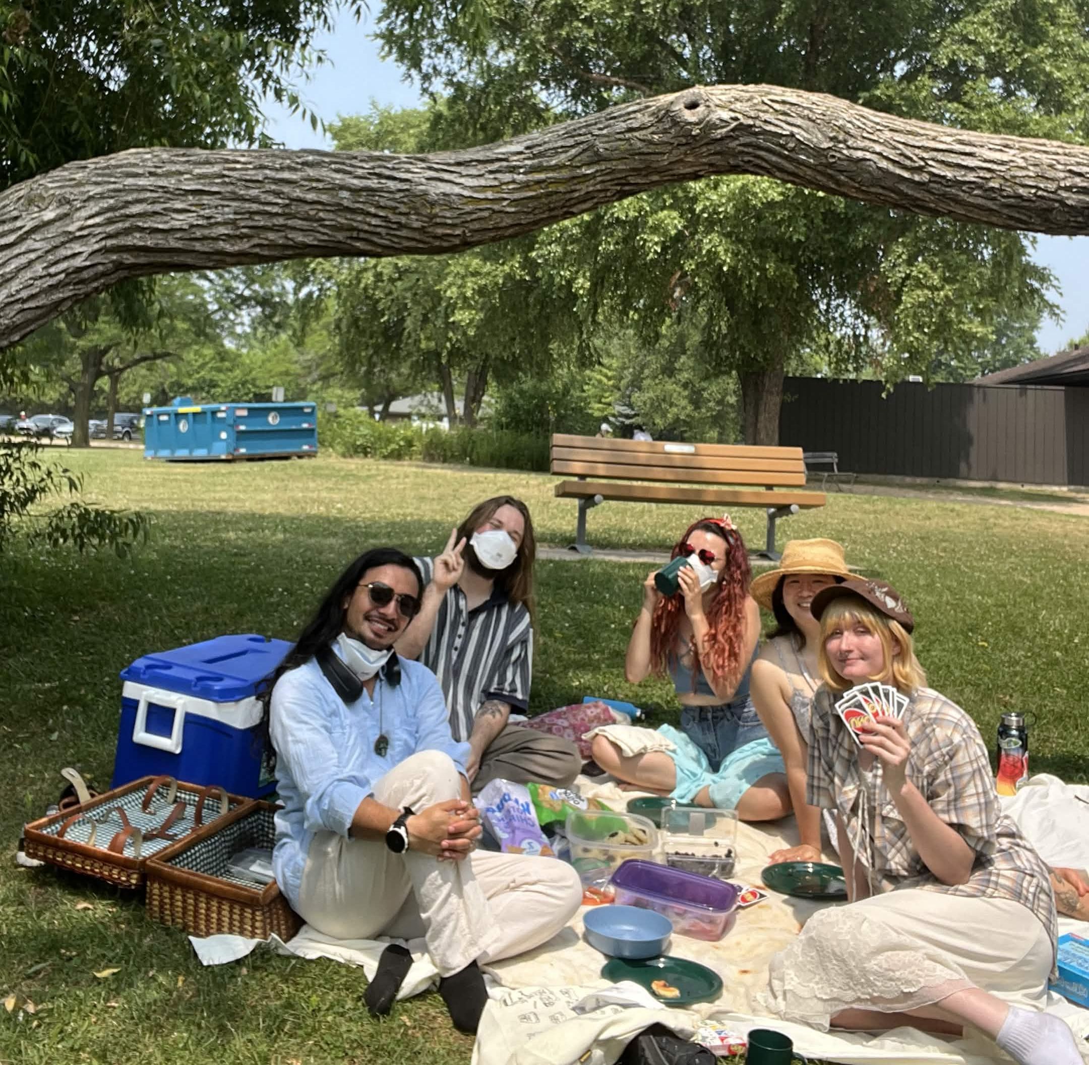 Five Summiteers having a picnic by the lake, some of them wearing facemasks